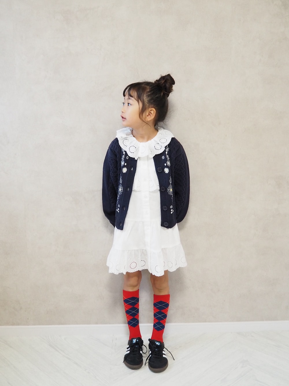 ホワイト系のワンピース、ブルー系のカーディガン/ボレロ、レッド系のソックス/靴下を着用したキッズの秋コーディネートの2枚目の写真