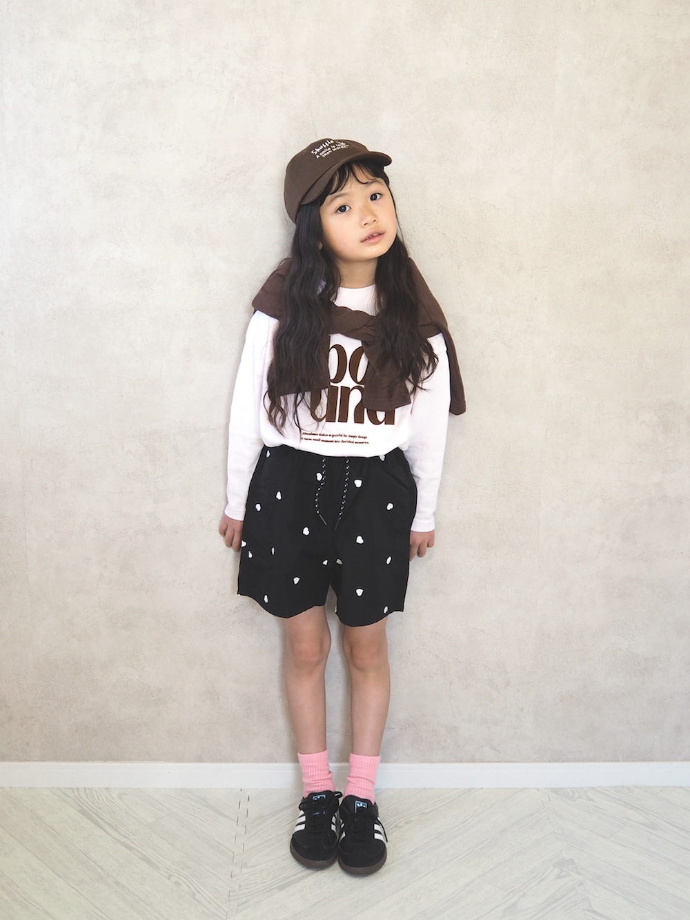 ブラウン系のカーディガン/ボレロ、ピンク系のTシャツ/カットソー、ブラック系のその他パンツを着用したキッズの春コーディネートの2枚目の写真