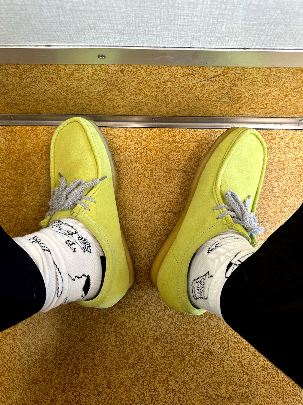 グリーン系のブーツ、ブルー系のスラックス、ベージュ系のトートバッグを着用したメンズの夏コーディネートの2枚目の写真