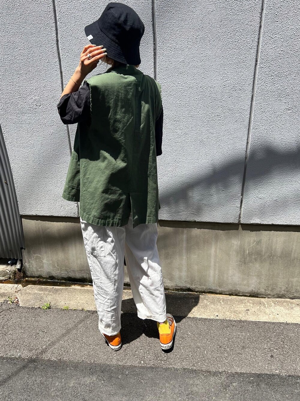 グリーン系のベスト、オレンジ系のスニーカー、グレー系のTシャツ/カットソーを着用したレディースの春コーディネートの3枚目の写真