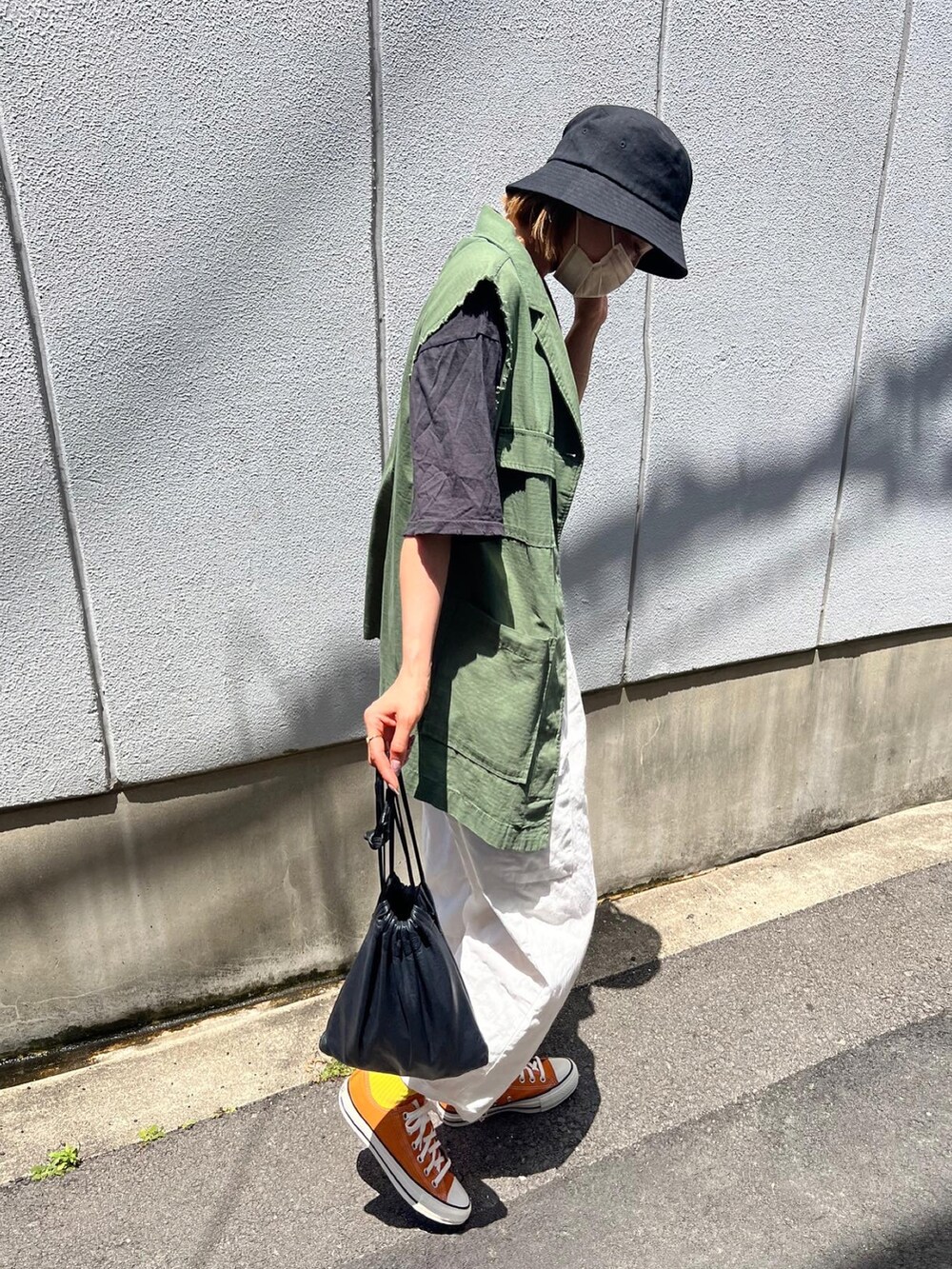 グリーン系のベスト、オレンジ系のスニーカー、グレー系のTシャツ/カットソーを着用したレディースの春コーディネートの2枚目の写真