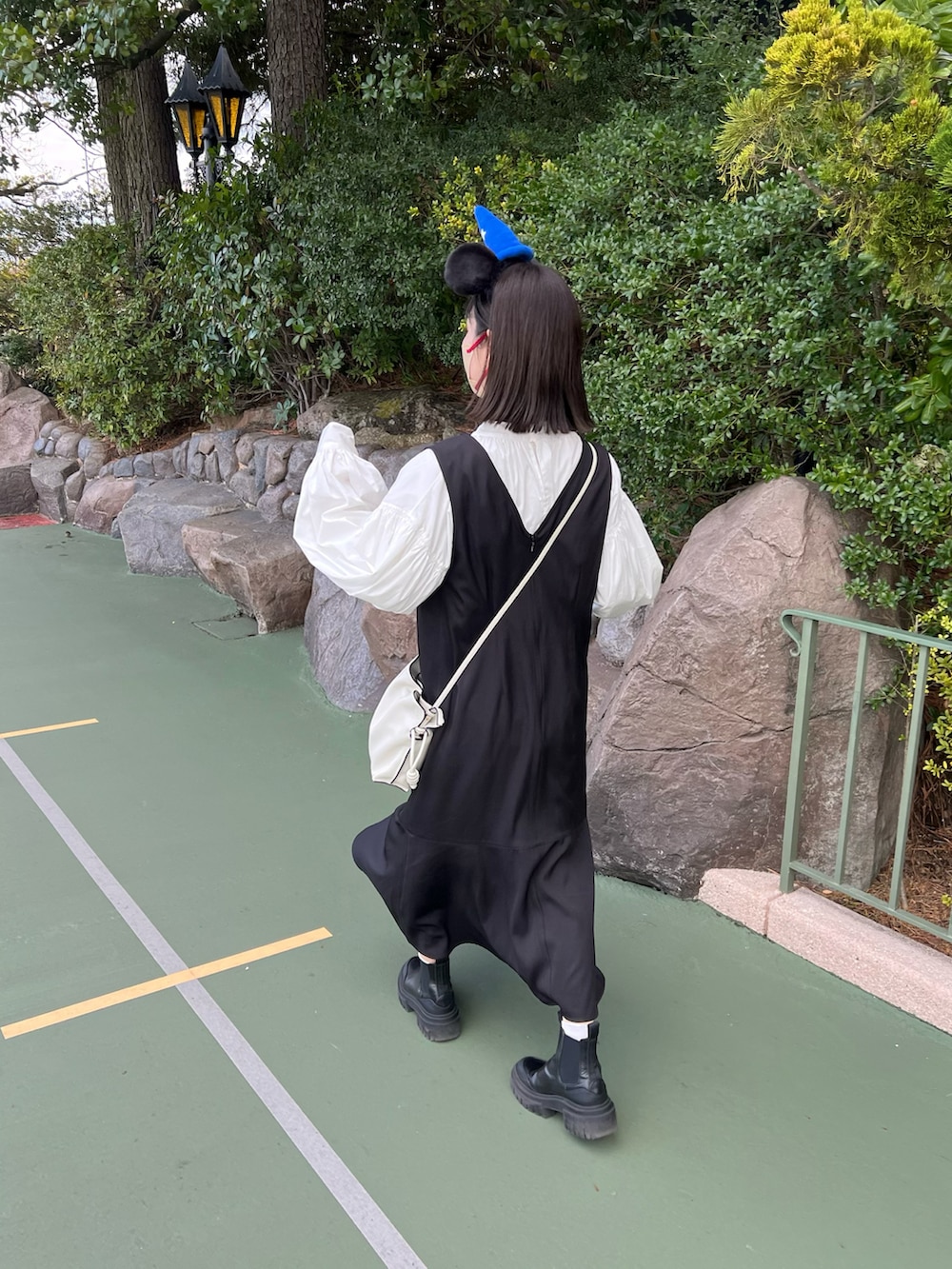 ブラック系のジャンパースカート、ホワイト系のシャツ/ブラウス、ブラック系のシューズを着用したレディースの春コーディネートの3枚目の写真