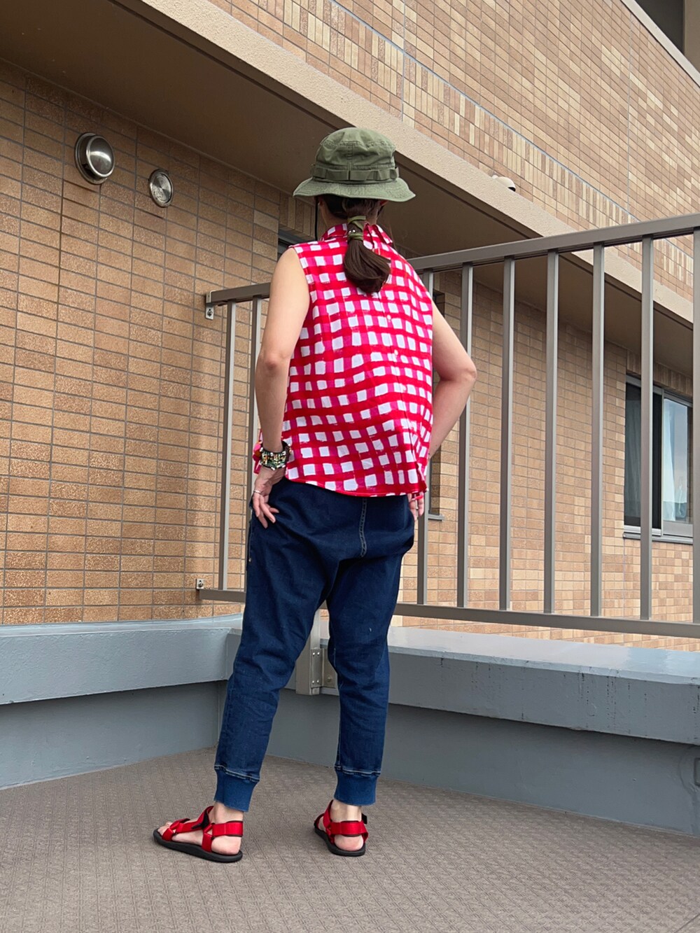 ブルー系のデニムパンツ、レッド系のシャツ/ブラウス、レッド系のサンダルを着用したレディースの夏コーディネートの2枚目の写真