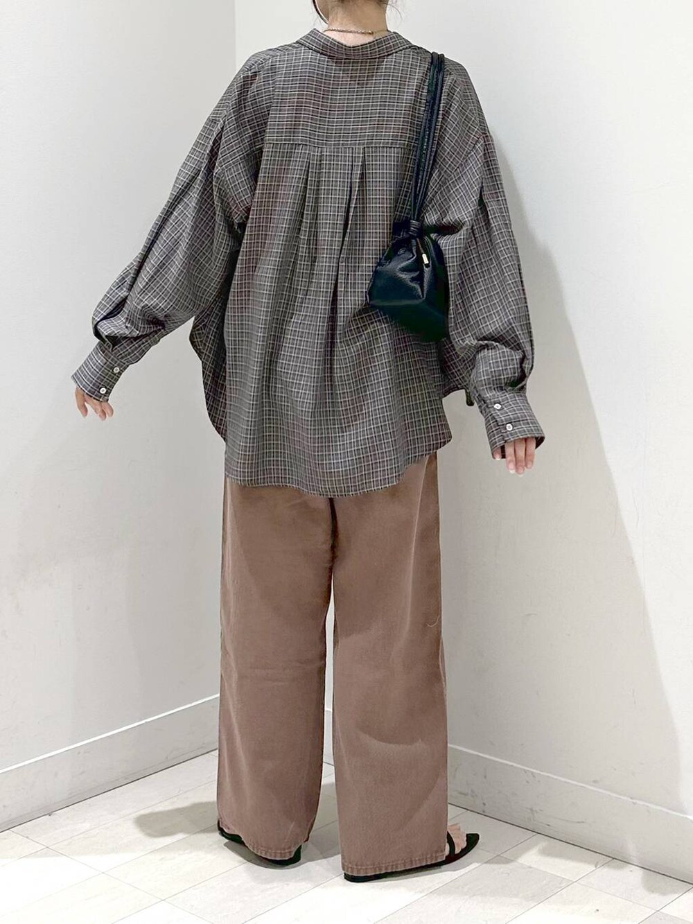 ブラック系のキャミソール、ブラック系のサンダル、ブラウン系のデニムパンツを着用したレディースの秋コーディネートの3枚目の写真