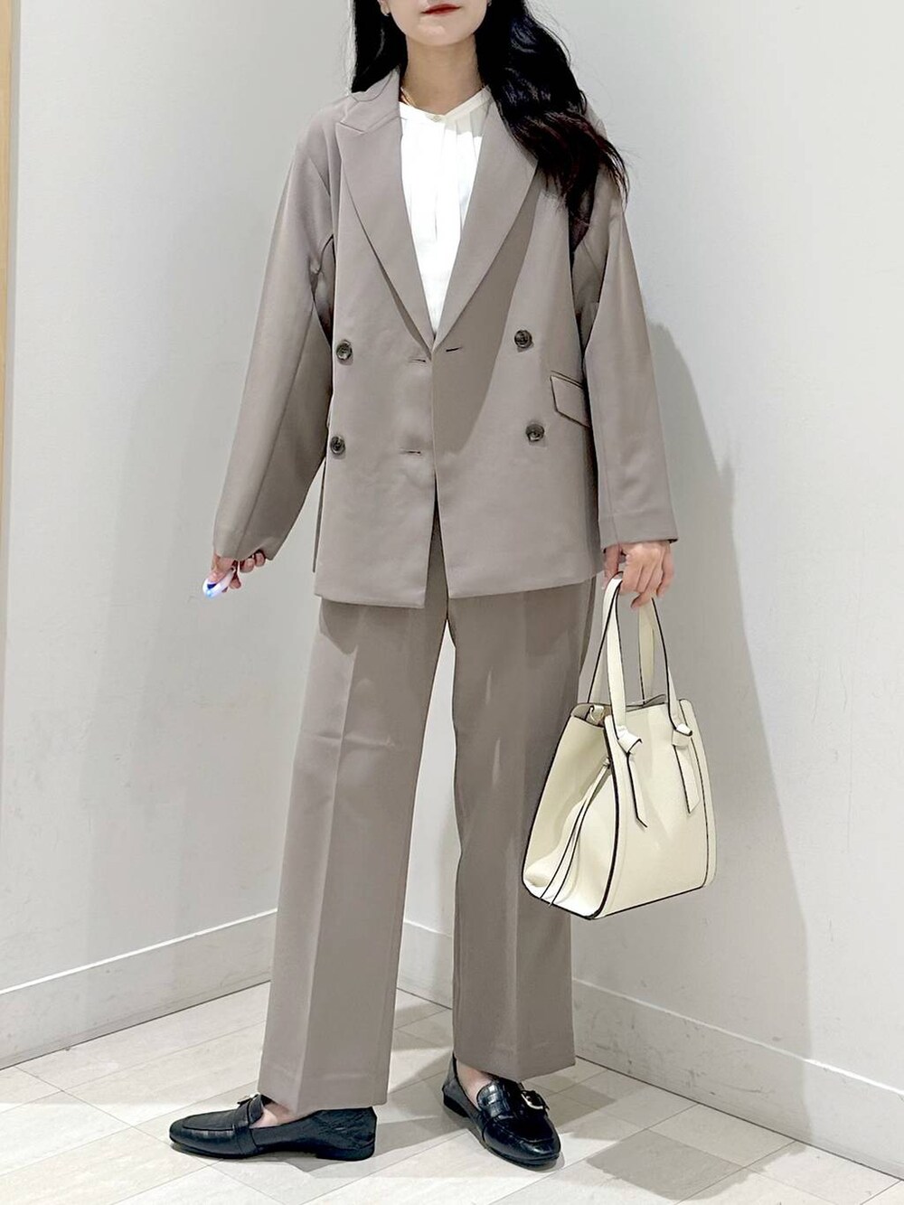 ブラック系のローファー、ホワイト系のショルダーバッグ、ブラウン系のスラックスを着用したレディースの秋コーディネートの4枚目の写真