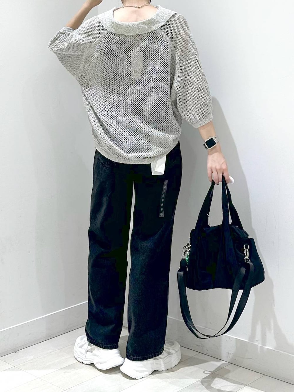 ブラック系のトートバッグ、ブラック系のデニムパンツ、ホワイト系のスニーカーを着用したレディースの秋コーディネートの3枚目の写真