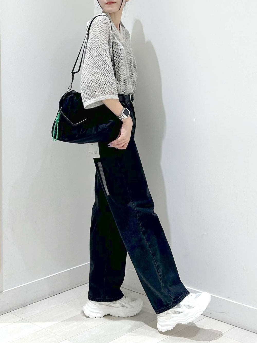 ブラック系のトートバッグ、ブラック系のデニムパンツ、ホワイト系のスニーカーを着用したレディースの秋コーディネートの2枚目の写真