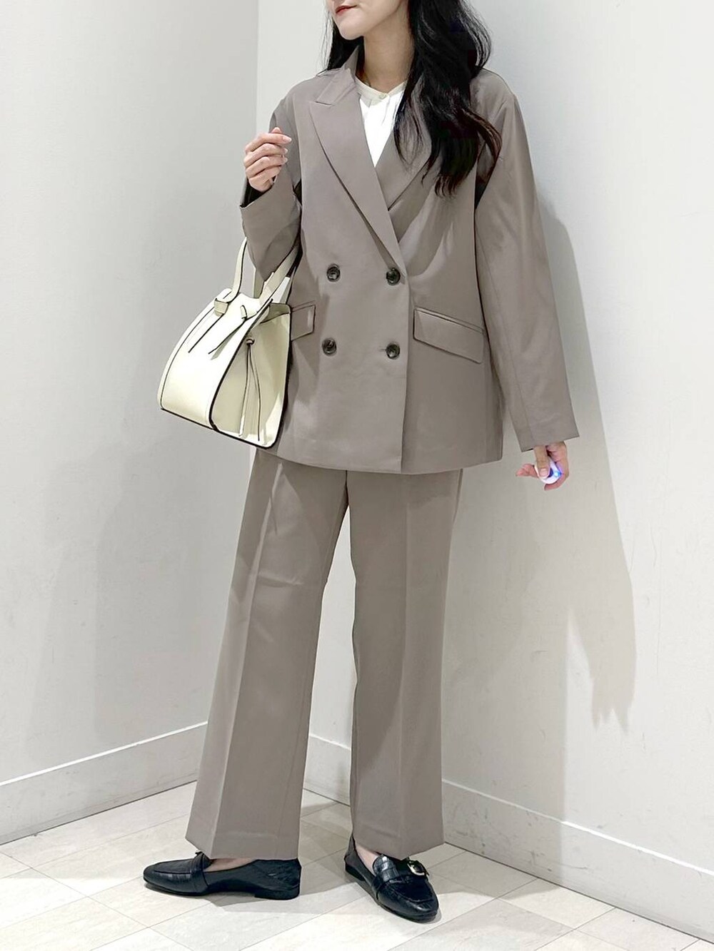 ブラック系のローファー、ホワイト系のショルダーバッグ、ブラウン系のスラックスを着用したレディースの秋コーディネートの5枚目の写真