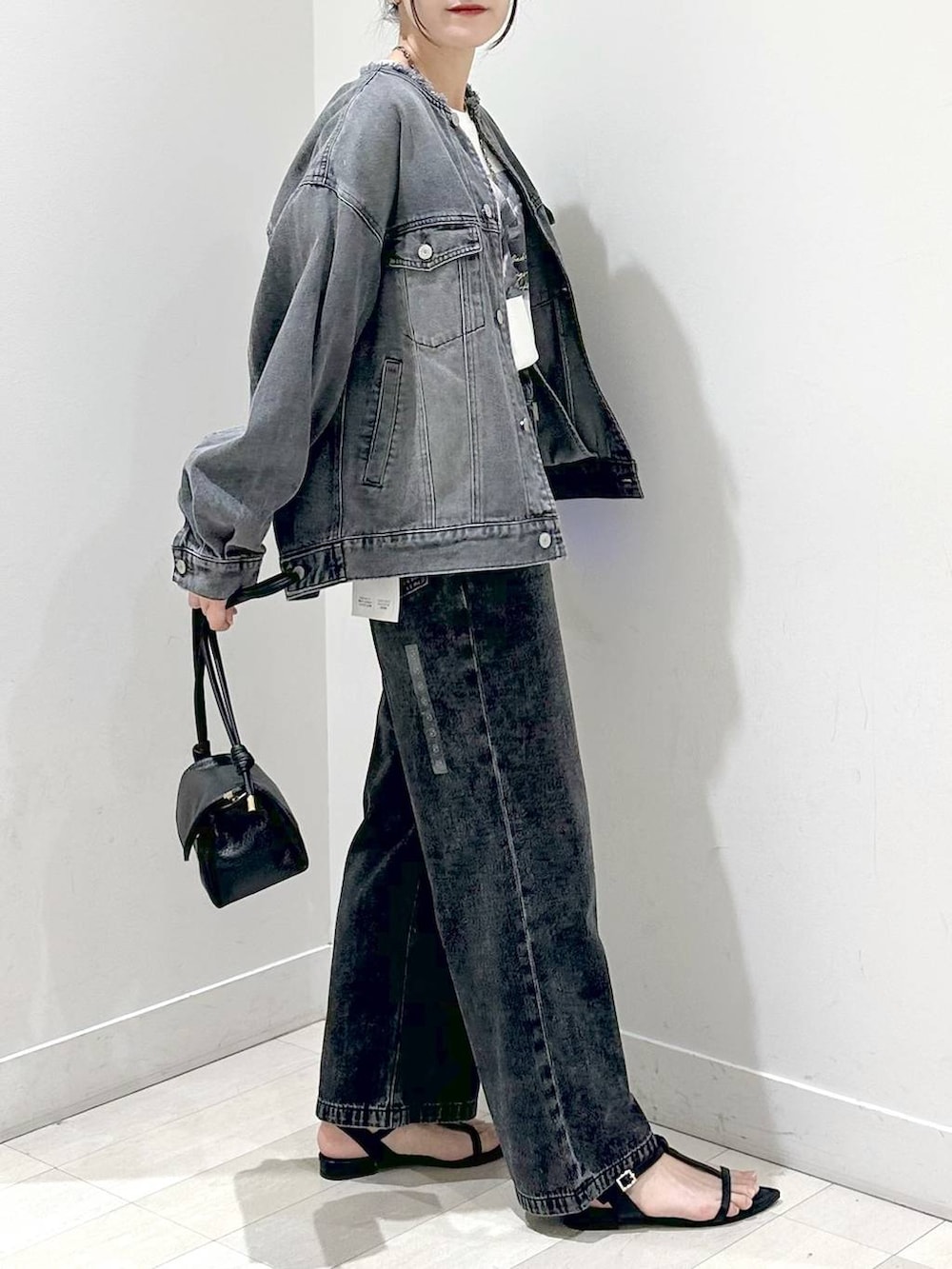 ホワイト系のTシャツ/カットソー、ブラック系のサンダル、ブラック系のデニムパンツを着用したレディースの秋コーディネートの2枚目の写真