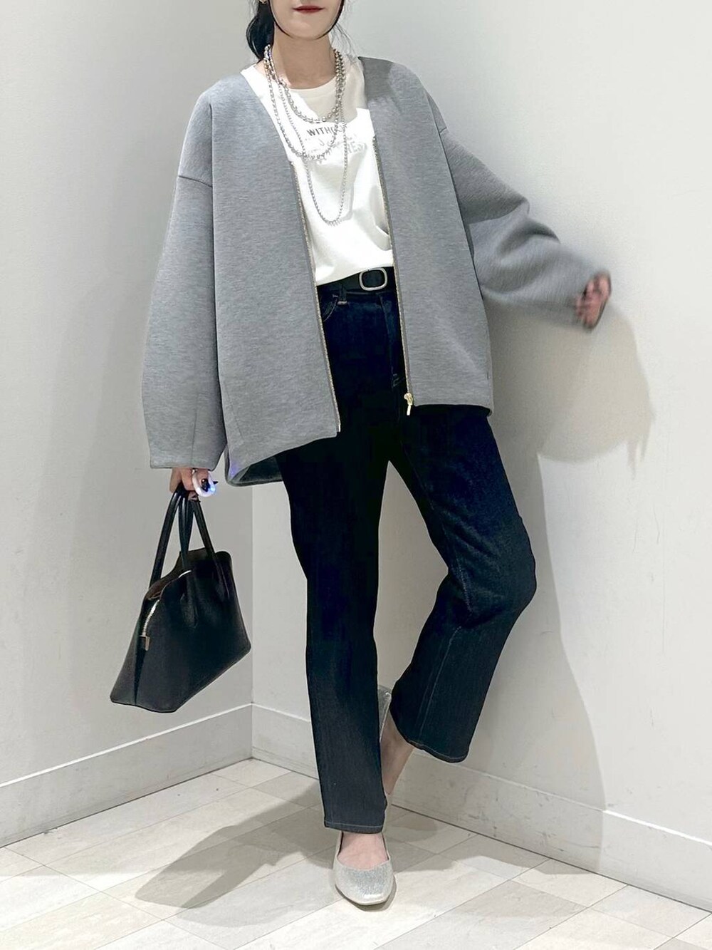 シルバー系のパンプス、ブルー系のショルダーバッグ、ブルー系のデニムパンツを着用したレディースの秋コーディネートの4枚目の写真