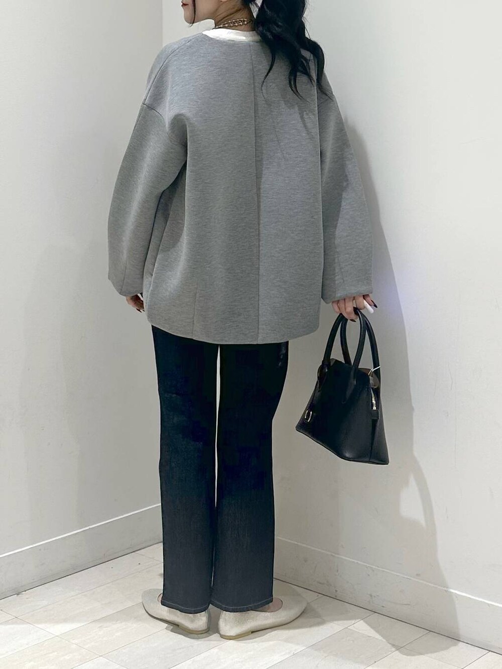 シルバー系のパンプス、ブルー系のショルダーバッグ、ブルー系のデニムパンツを着用したレディースの秋コーディネートの3枚目の写真