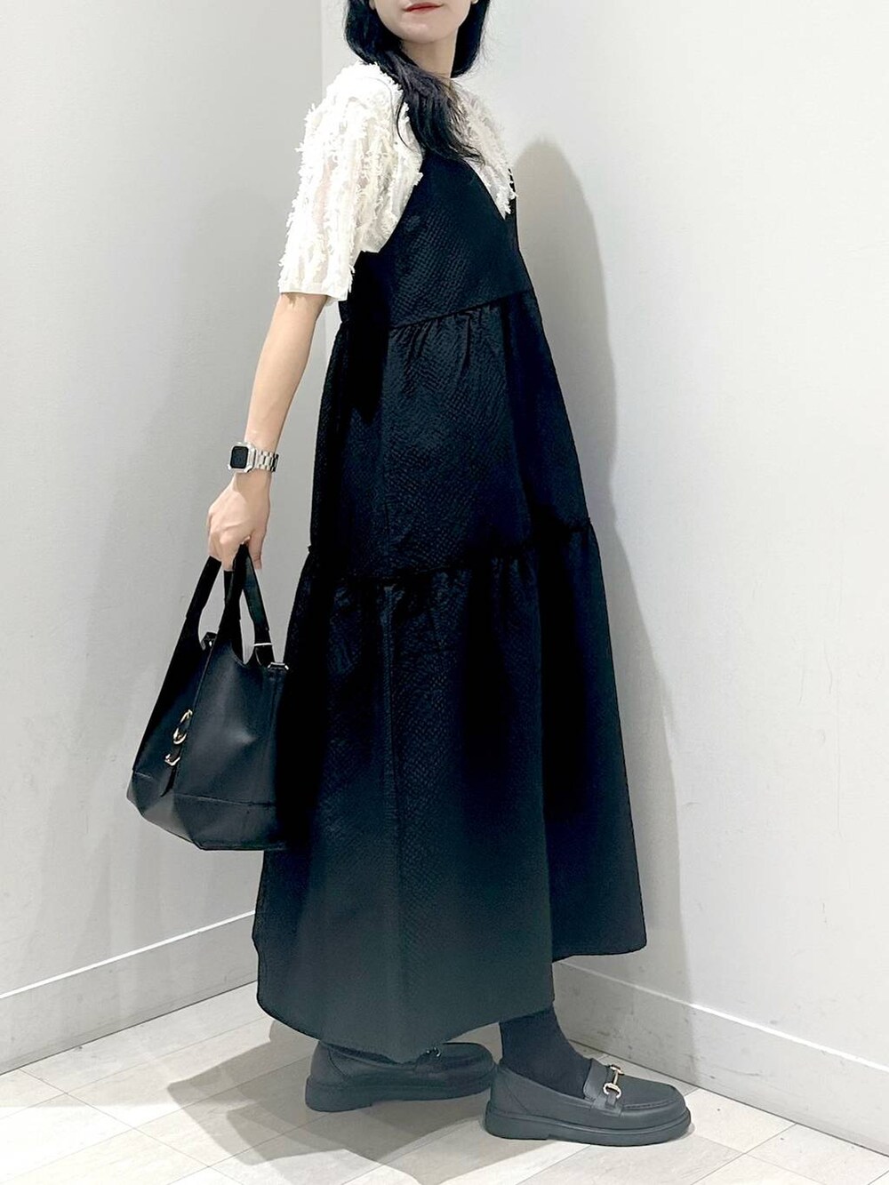 ブラック系のショルダーバッグ、ブラック系のワンピース、ホワイト系のTシャツ/カットソーを着用したレディースの夏コーディネートの2枚目の写真