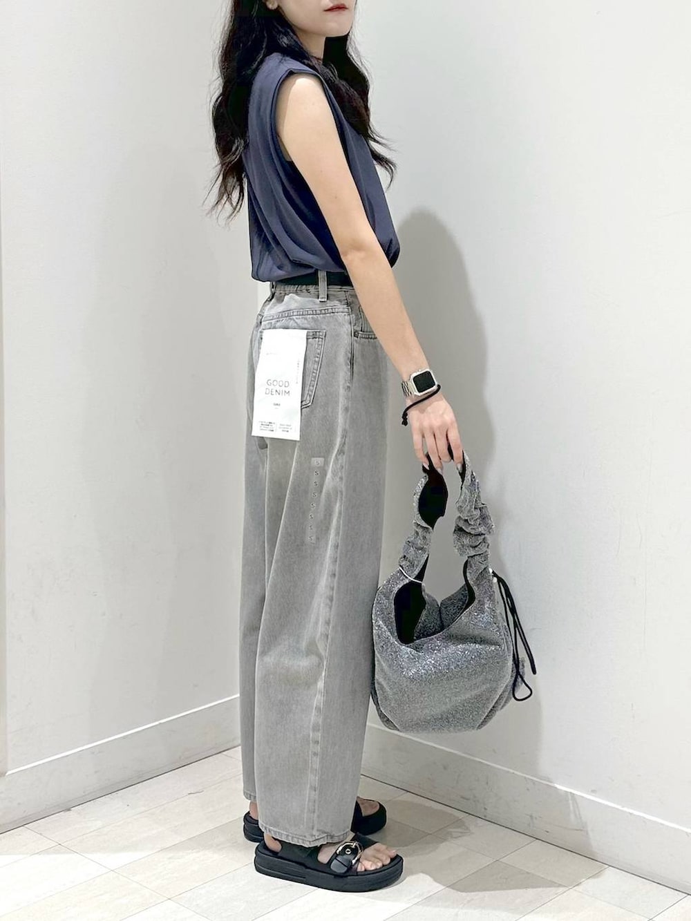 グレー系のデニムパンツ、ブラック系のサンダルを着用したレディースの夏コーディネートの2枚目の写真