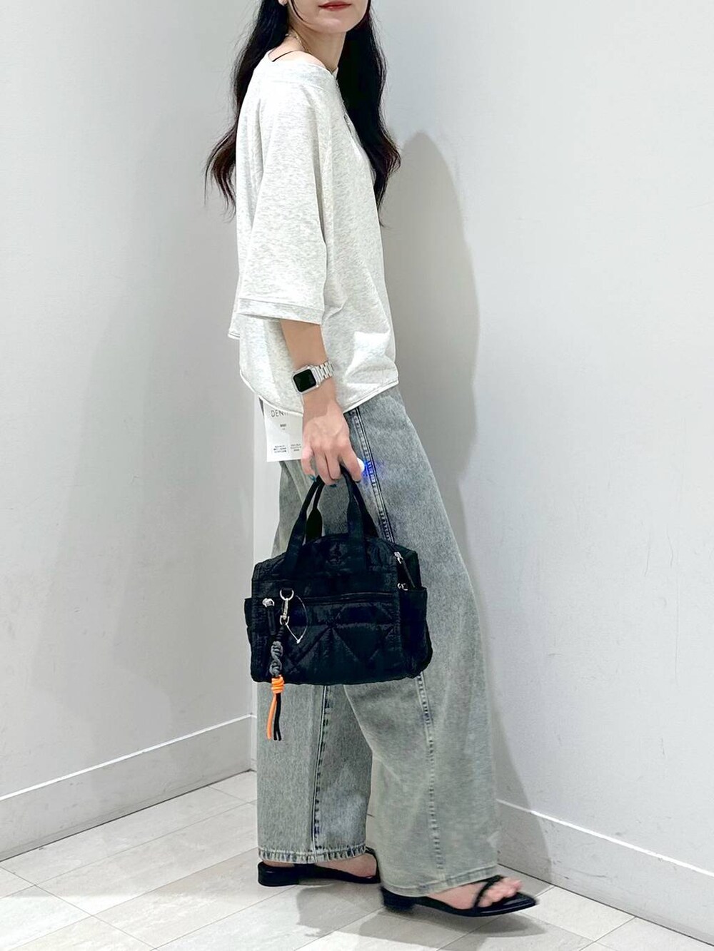 ブラック系のサンダル、ブルー系のデニムパンツ、ブラック系のボストンバッグを着用したレディースの夏コーディネートの2枚目の写真