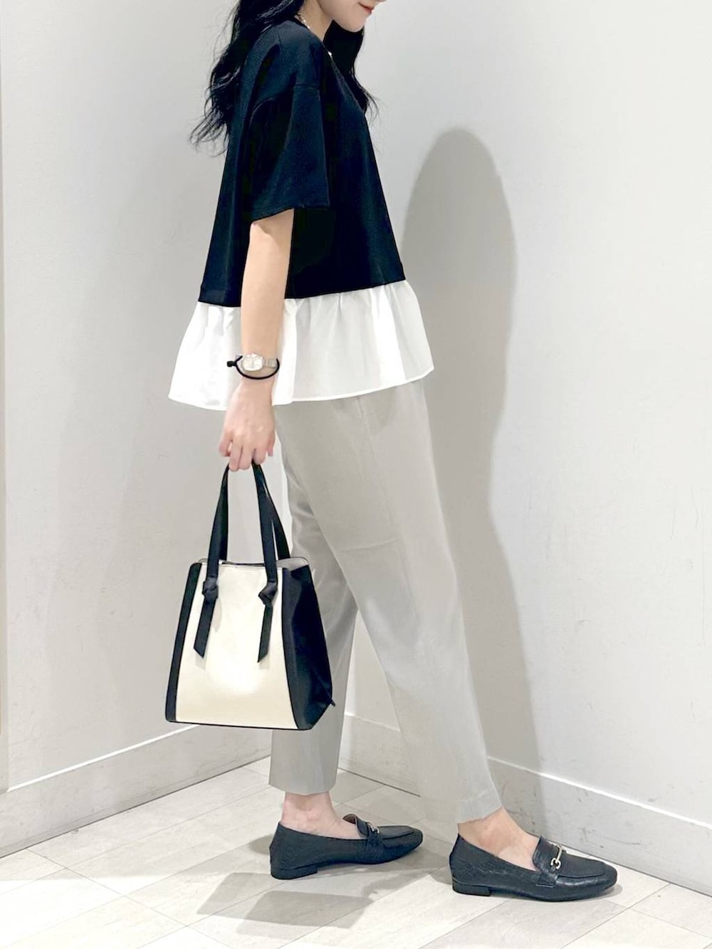 ブラック系のローファー、ホワイト系のショルダーバッグ、ブラック系のTシャツ/カットソーを着用したレディースの夏コーディネートの2枚目の写真