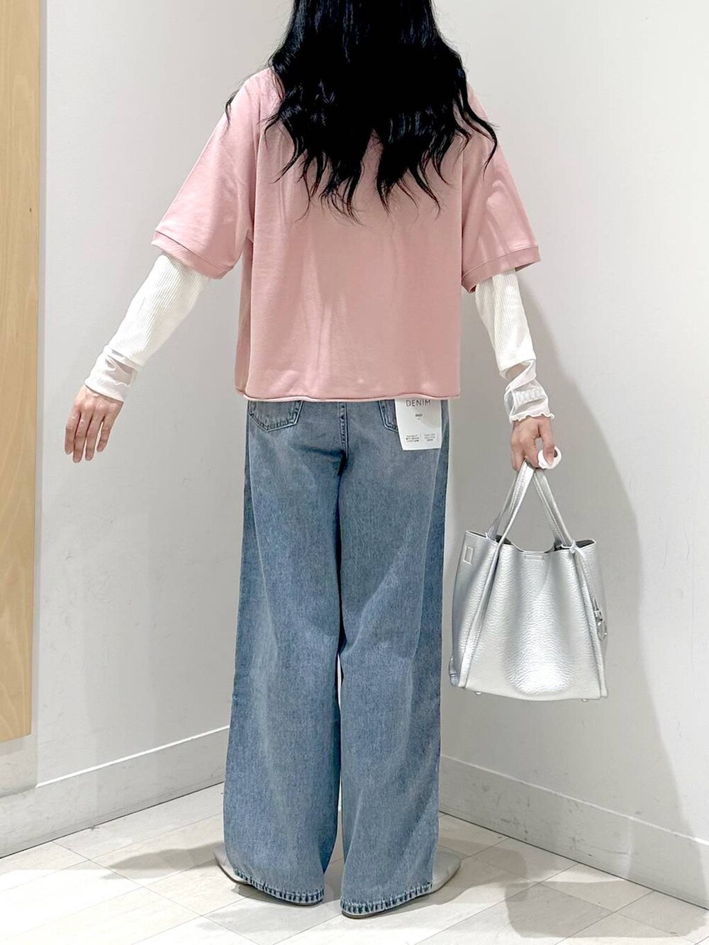 ブルー系のデニムパンツ、ピンク系のTシャツ/カットソー、シルバー系のトートバッグを着用したレディースの秋コーディネートの3枚目の写真