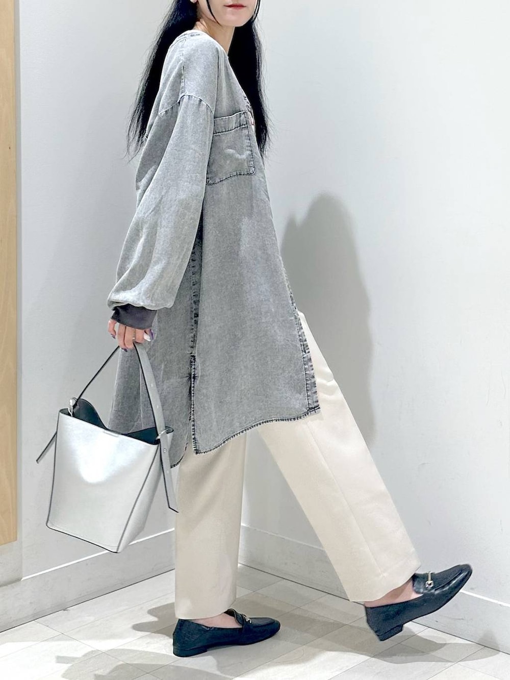 ブラック系のローファー、シルバー系のショルダーバッグ、ベージュ系のスラックスを着用したレディースの秋コーディネートの2枚目の写真