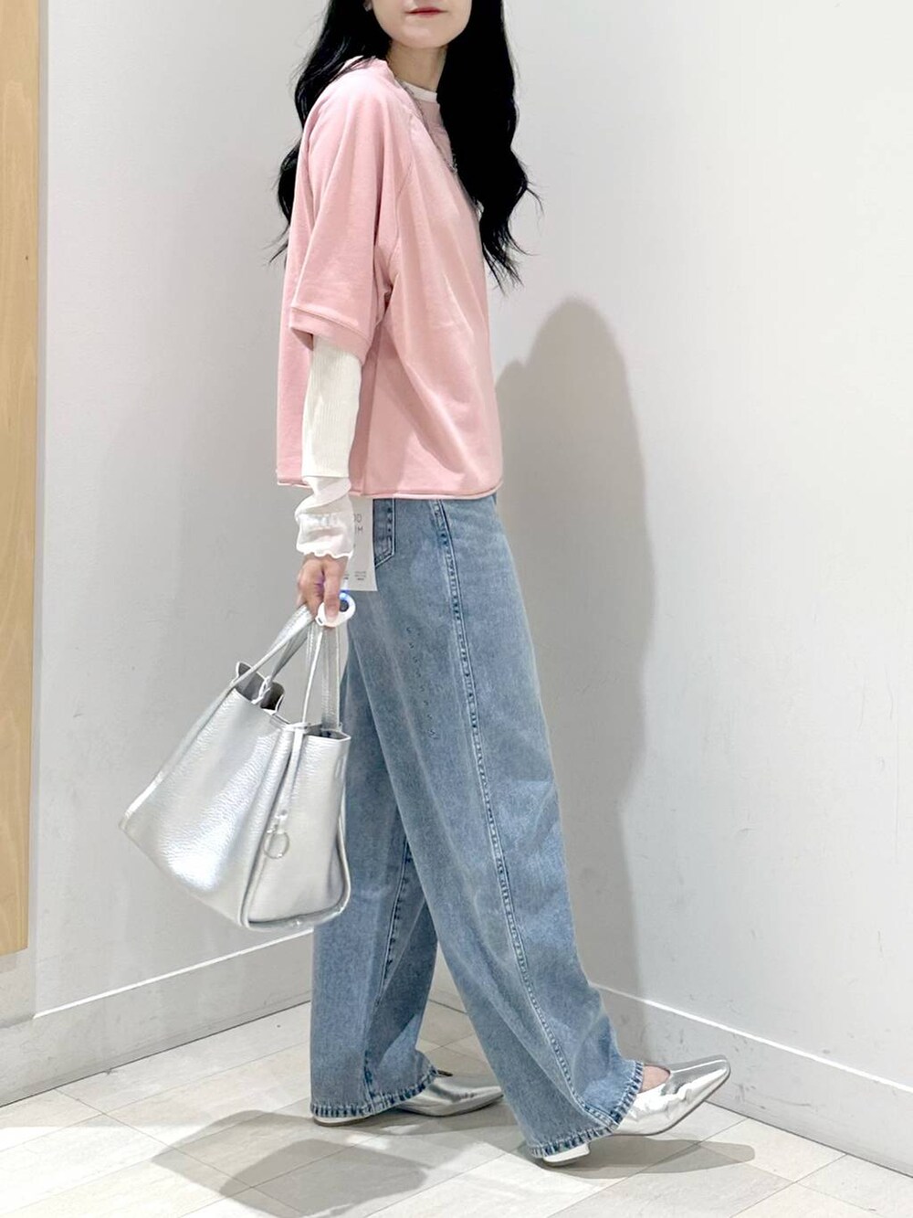 ブルー系のデニムパンツ、ピンク系のTシャツ/カットソー、シルバー系のトートバッグを着用したレディースの秋コーディネートの2枚目の写真