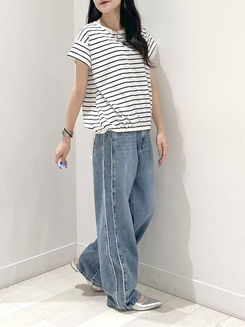ブルー系のデニムパンツ、シルバー系のサンダル、ホワイト系のTシャツ/カットソーを着用したレディースの夏コーディネートの2枚目の写真