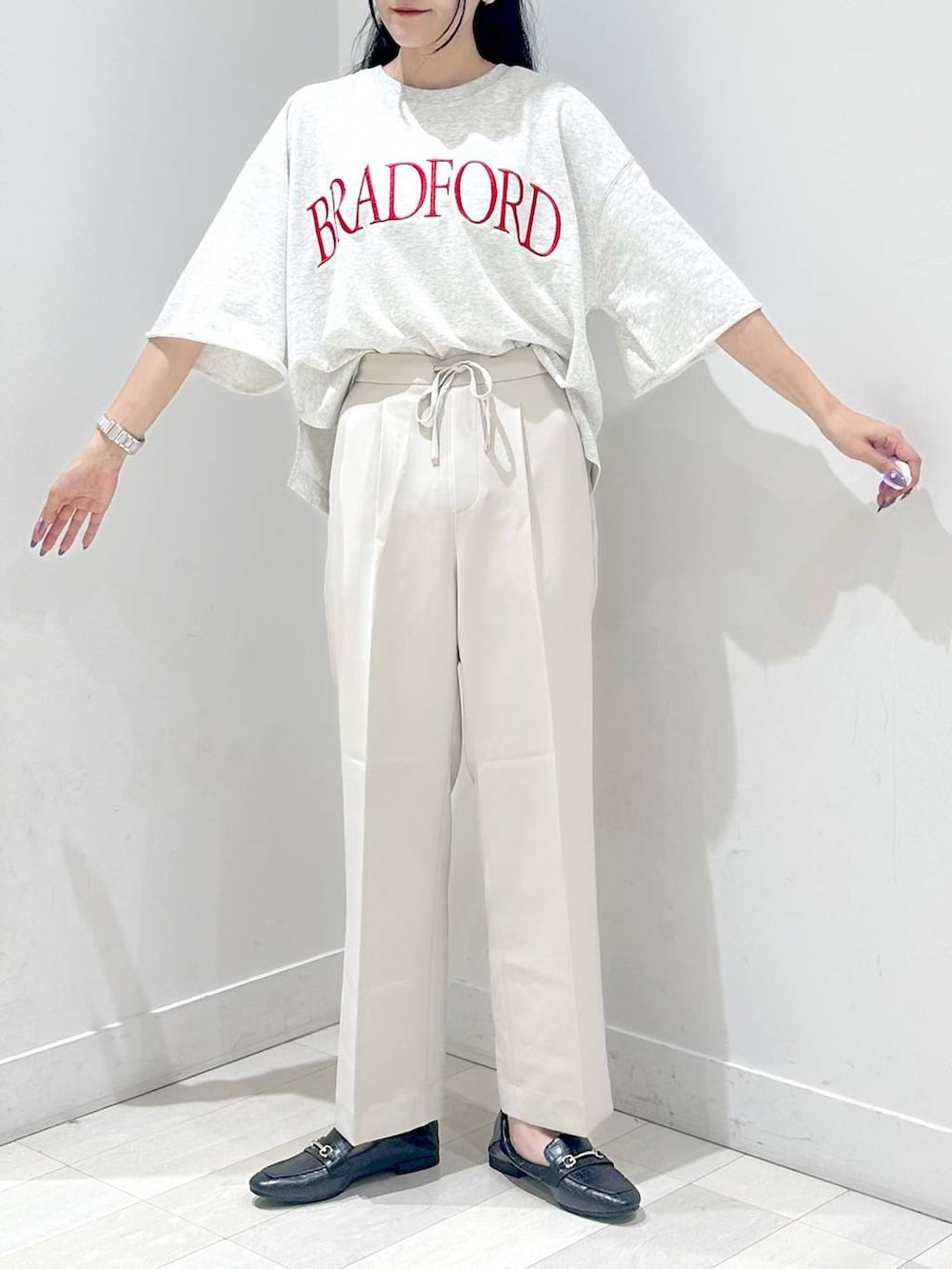 ブラック系のローファー、シルバー系のショルダーバッグ、ベージュ系のスラックスを着用したレディースの秋コーディネートの4枚目の写真