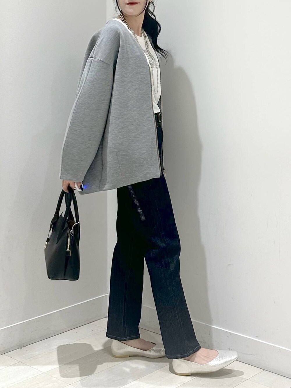 シルバー系のパンプス、ブルー系のショルダーバッグ、ブルー系のデニムパンツを着用したレディースの秋コーディネートの2枚目の写真