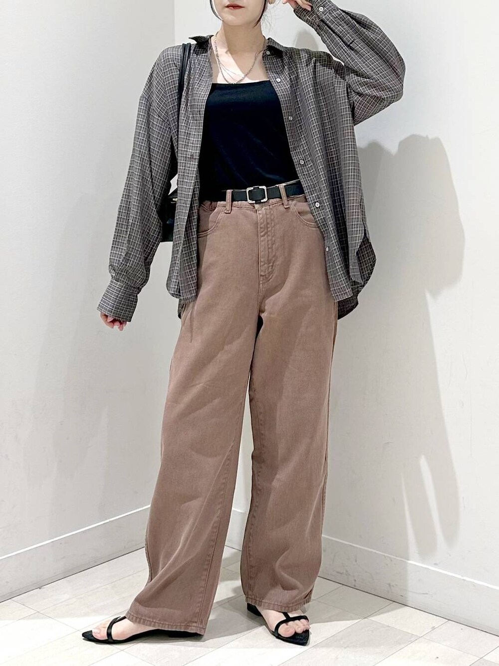 ブラック系のキャミソール、ブラック系のサンダル、ブラウン系のデニムパンツを着用したレディースの秋コーディネートの4枚目の写真