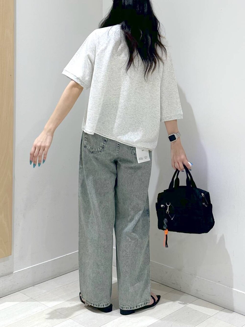 ブラック系のサンダル、ブルー系のデニムパンツ、ブラック系のボストンバッグを着用したレディースの夏コーディネートの3枚目の写真