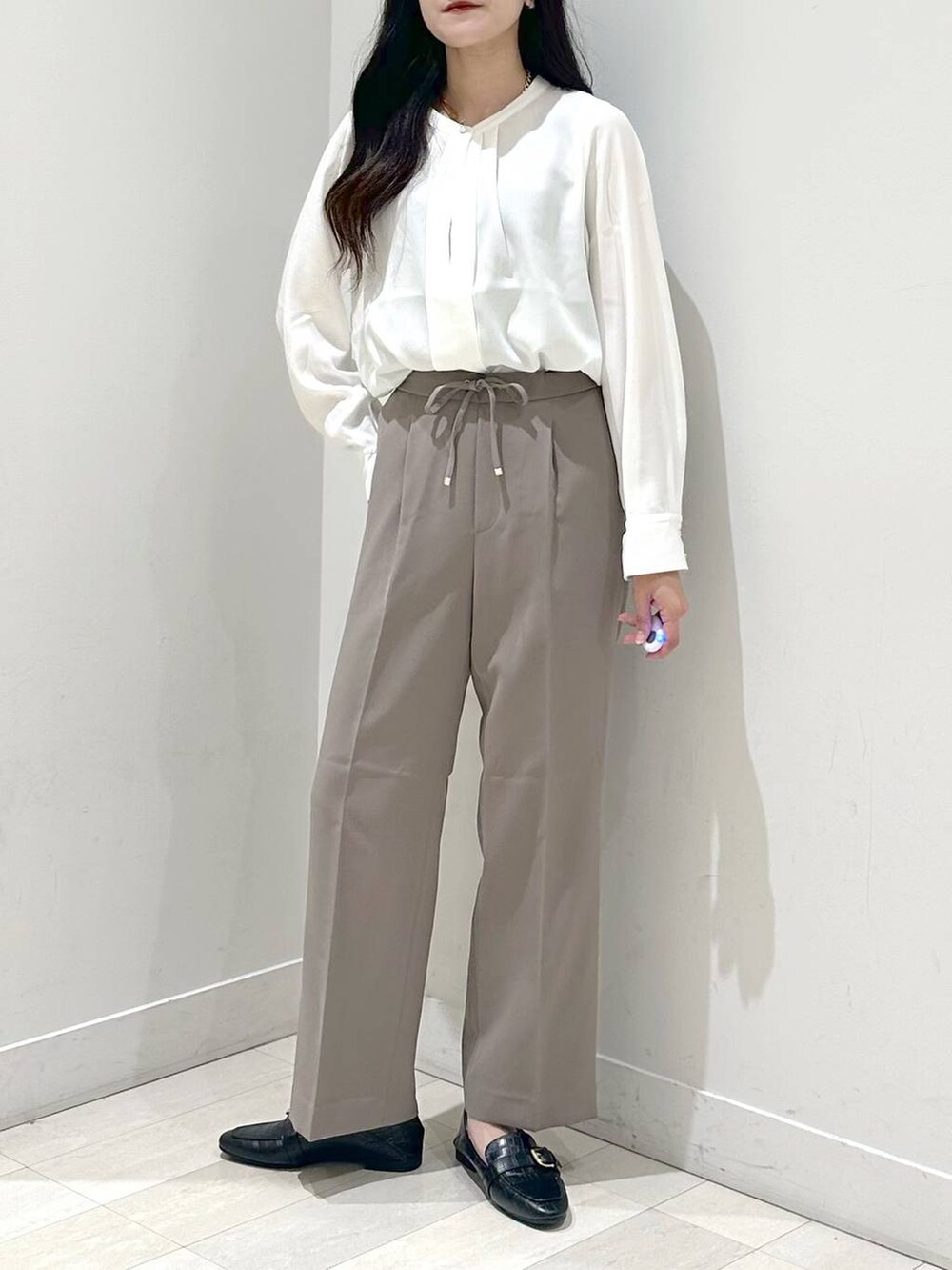 ブラック系のローファー、ホワイト系のショルダーバッグ、ブラウン系のスラックスを着用したレディースの秋コーディネートの6枚目の写真