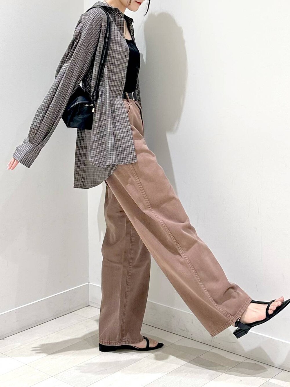 ブラック系のキャミソール、ブラック系のサンダル、ブラウン系のデニムパンツを着用したレディースの秋コーディネートの2枚目の写真