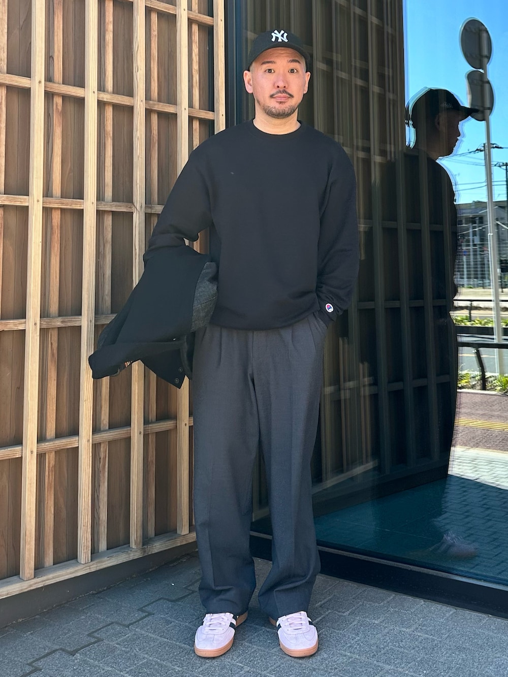 ブラック系のスウェット、ブラック系のスタジャン、グレー系のスラックスを着用したメンズの冬コーディネートの2枚目の写真