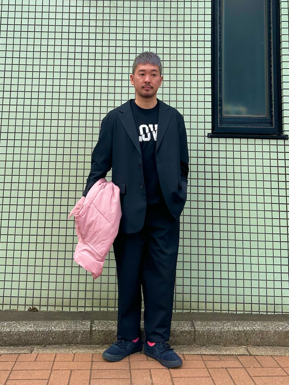 ピンク系のダウンベスト、ブラック系のテーラードジャケット、ブラック系のスラックスを着用したメンズの秋コーディネートの2枚目の写真