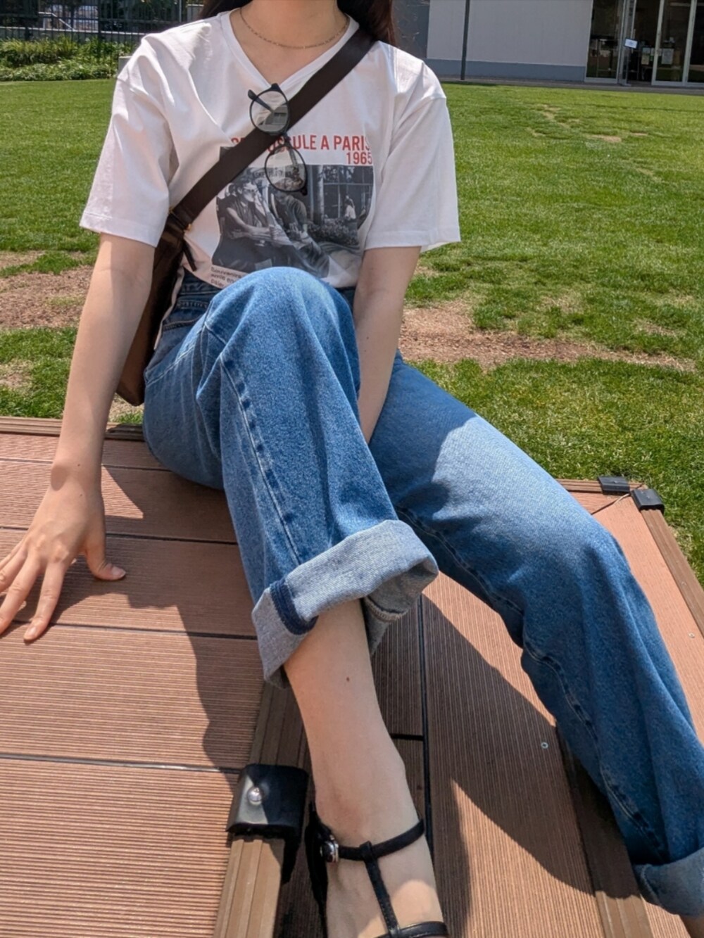 ホワイト系のTシャツ/カットソー、ブラウン系のトートバッグ、ブルー系のデニムパンツを着用したレディースの夏コーディネートの2枚目の写真