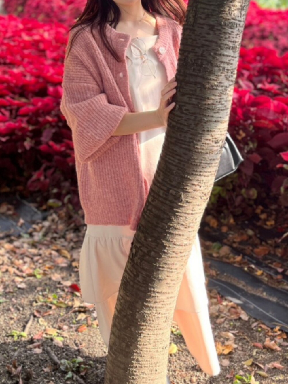 ピンク系のカーディガン/ボレロ、ホワイト系のワンピース、ブラック系のバッグを着用したレディースの秋コーディネートの2枚目の写真