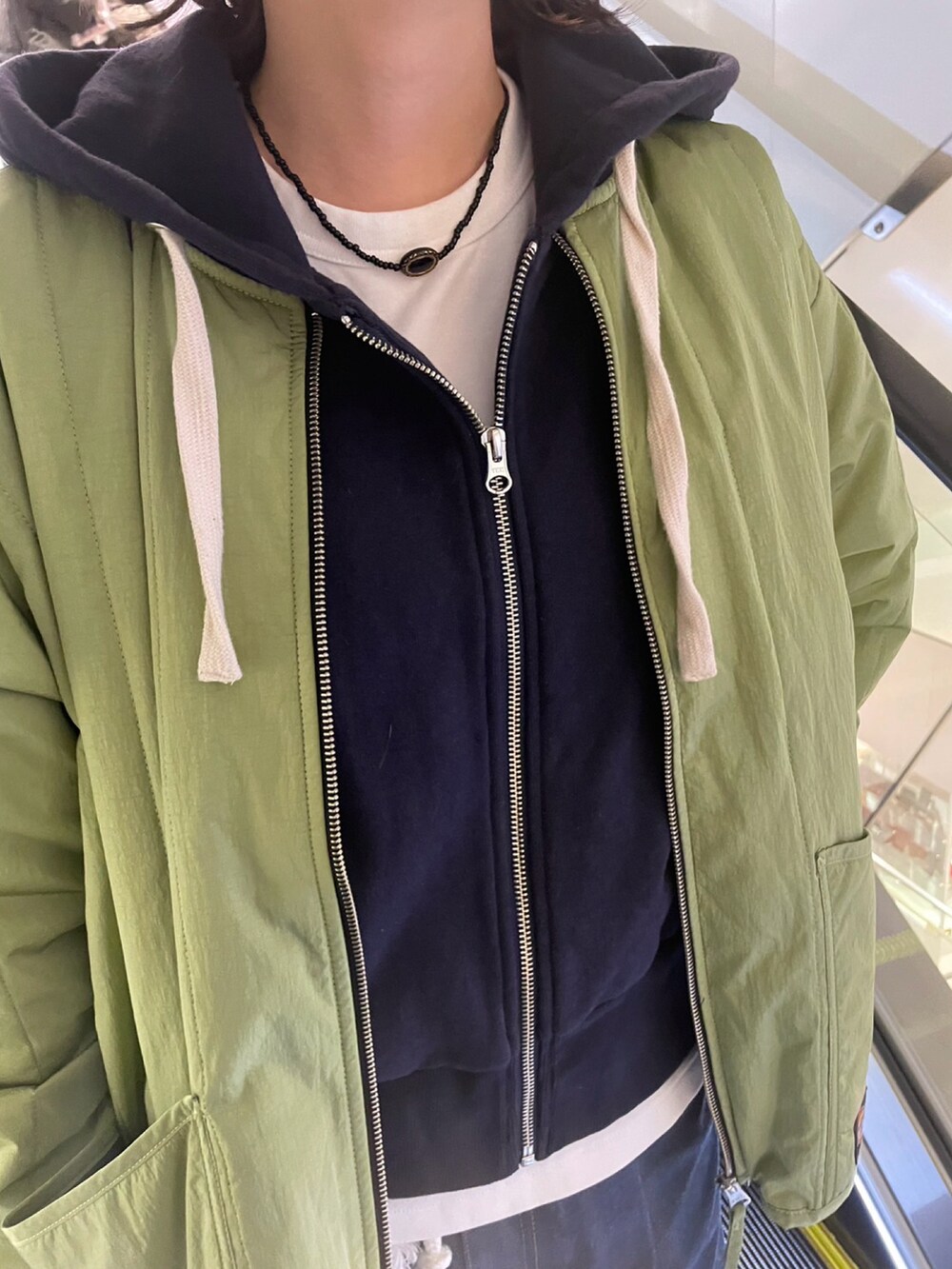 ホワイト系のスニーカー、ブルー系のデニムパンツ、グリーン系のショルダーバッグを着用したレディースの冬コーディネートの2枚目の写真