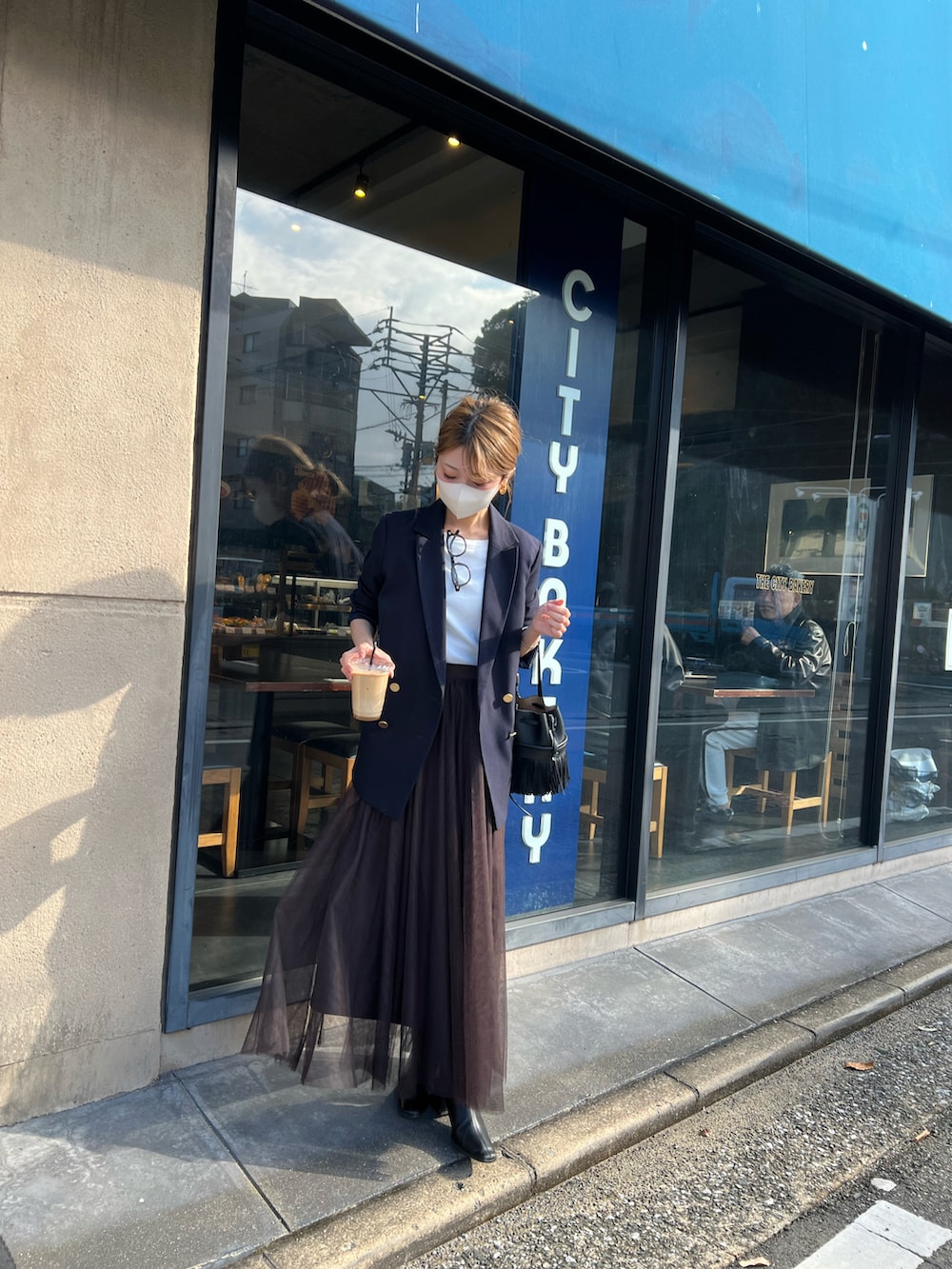 ブラウン系のスカート、ブルー系のテーラードジャケット、ブラック系のバッグを着用したレディースの冬コーディネートの2枚目の写真