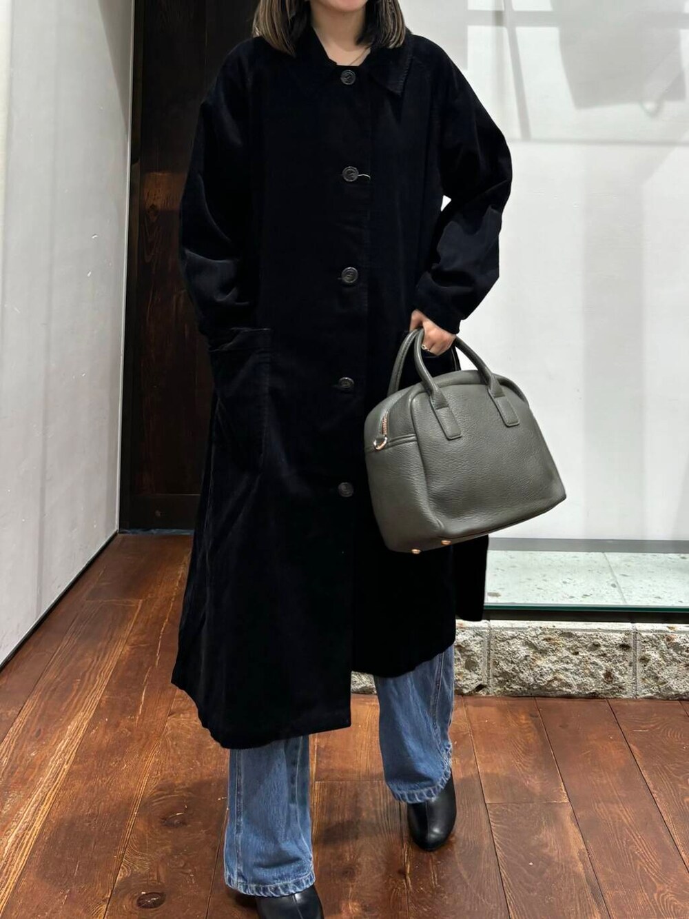 グリーン系のボストンバッグ、ブラック系のその他シューズ、ブラック系のステンカラーコートを着用したレディースの秋コーディネートの4枚目の写真