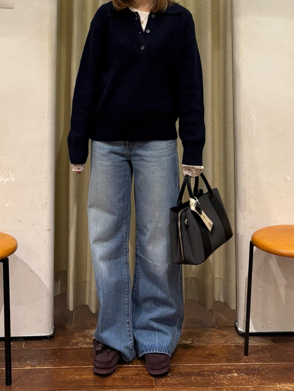 ブルー系のニット/セーター、ブルー系のデニムパンツ、ブラック系のハンドバッグを着用したレディースの冬コーディネートの4枚目の写真