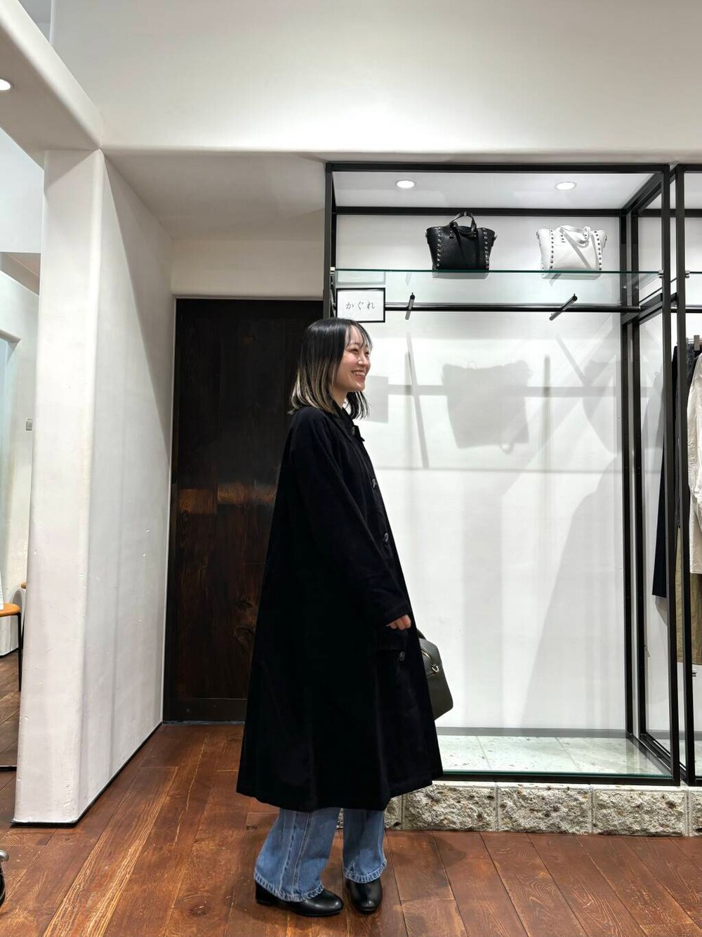 グリーン系のボストンバッグ、ブラック系のその他シューズ、ブラック系のステンカラーコートを着用したレディースの秋コーディネートの2枚目の写真