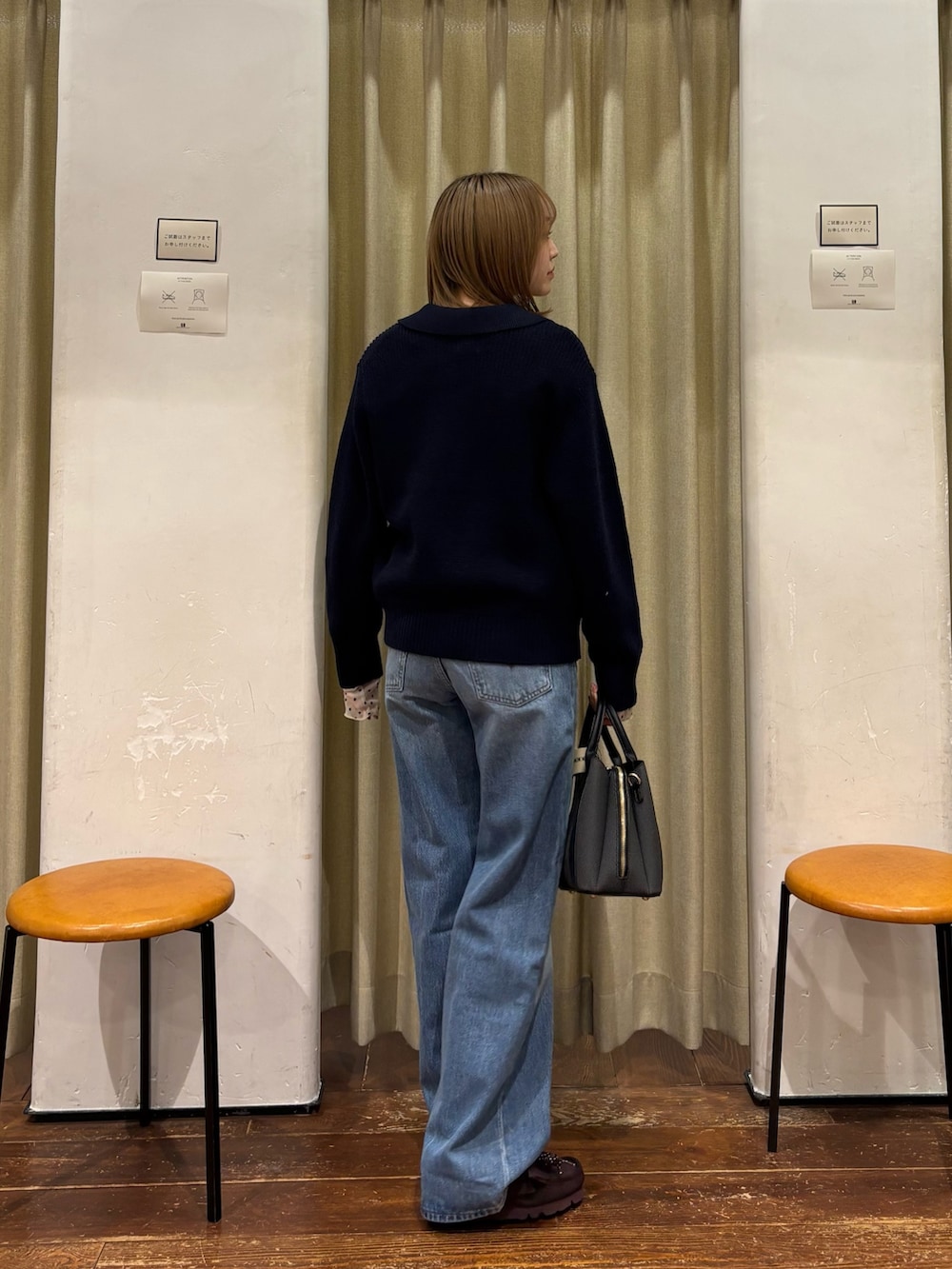 ブルー系のニット/セーター、ブルー系のデニムパンツ、ブラック系のハンドバッグを着用したレディースの冬コーディネートの3枚目の写真