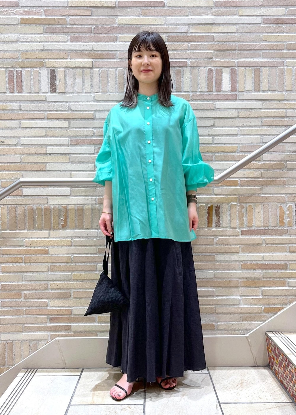 グリーン系のシャツ/ブラウス、ブラック系のサンダル、ブラック系のスカートを着用したレディースの春コーディネートの3枚目の写真