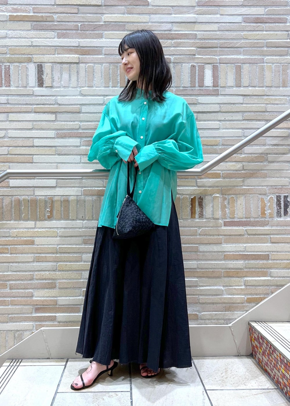 グリーン系のシャツ/ブラウス、ブラック系のサンダル、ブラック系のスカートを着用したレディースの春コーディネートの2枚目の写真