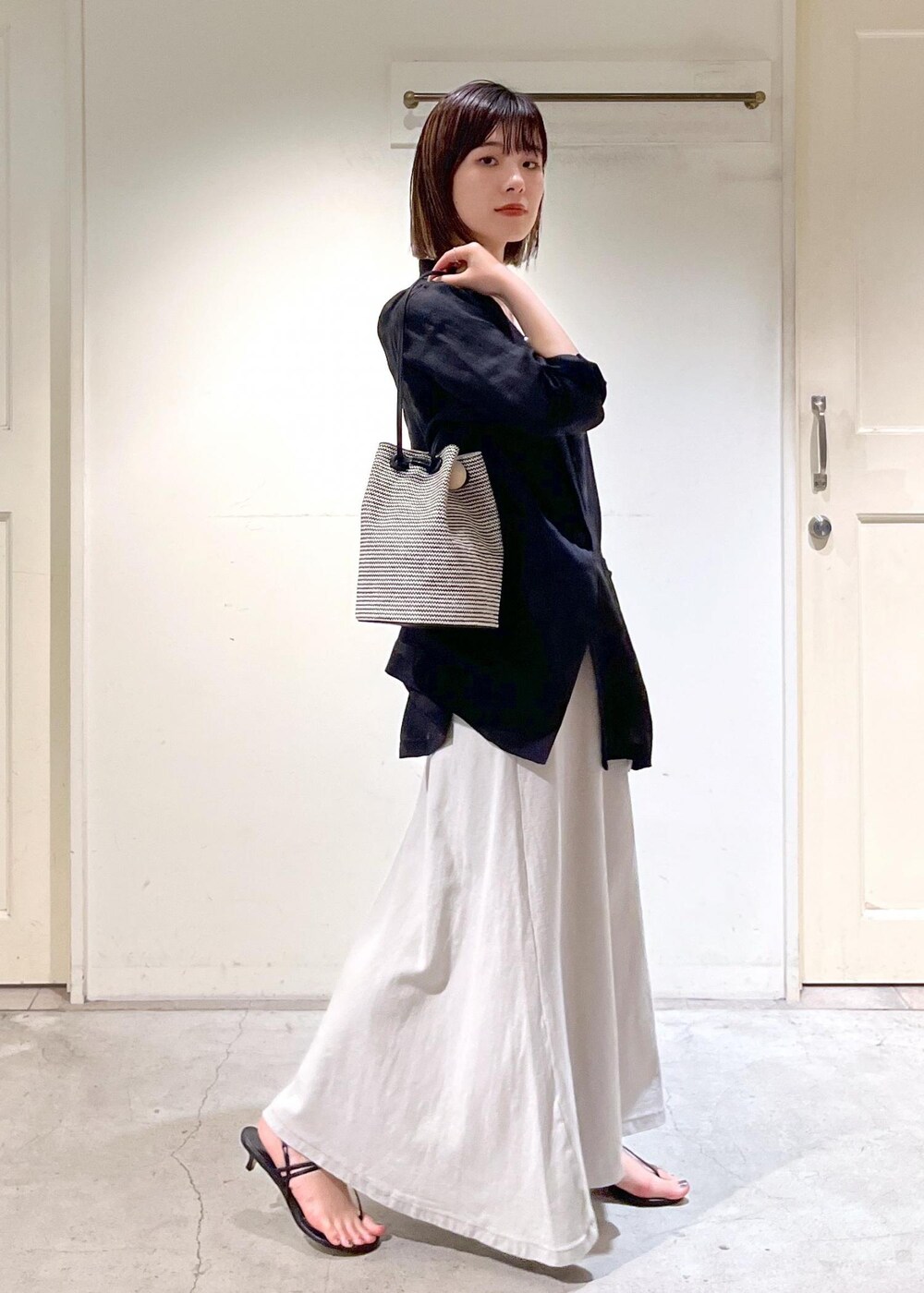 ブラック系のキャミソール、ブラック系のサンダル、ブラック系のショルダーバッグを着用したレディースの春コーディネートの6枚目の写真