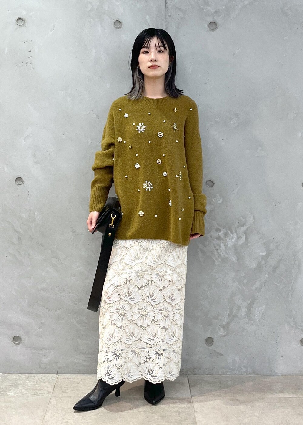 ブラック系のショルダーバッグ、ベージュ系のスカート、イエロー系のニット/セーターを着用したレディースの秋コーディネートの2枚目の写真