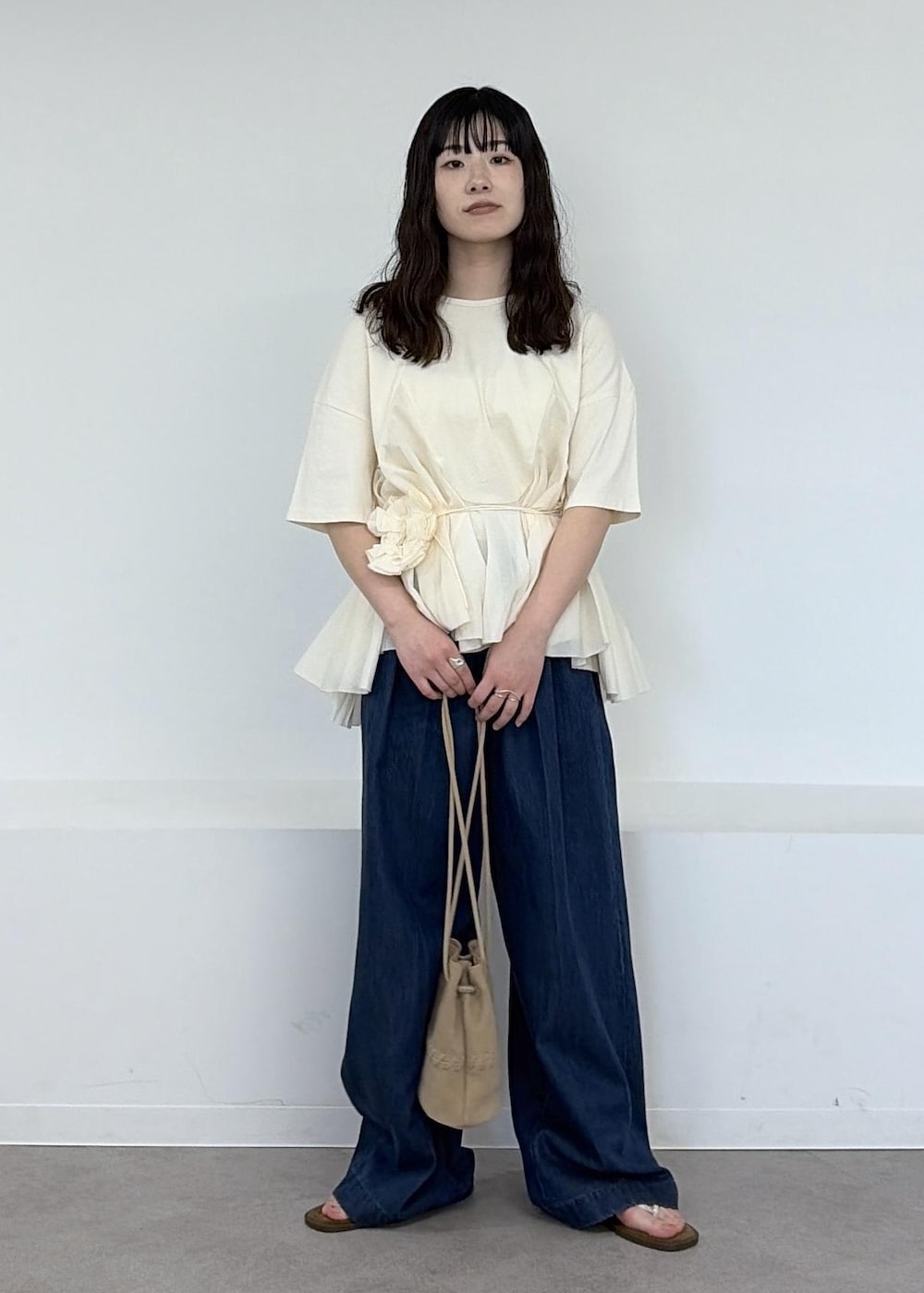 ベージュ系のショルダーバッグ、ブルー系のデニムパンツ、ブラウン系のサンダルを着用したレディースの冬コーディネートの2枚目の写真