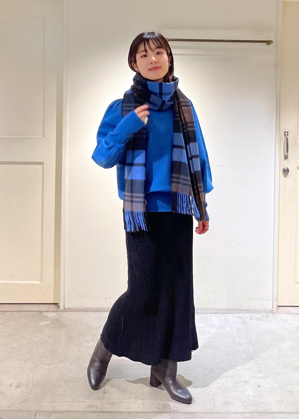 ブラック系のブーツ、ブラック系のスカート、ブルー系のニット/セーターを着用したレディースの秋コーディネートの2枚目の写真