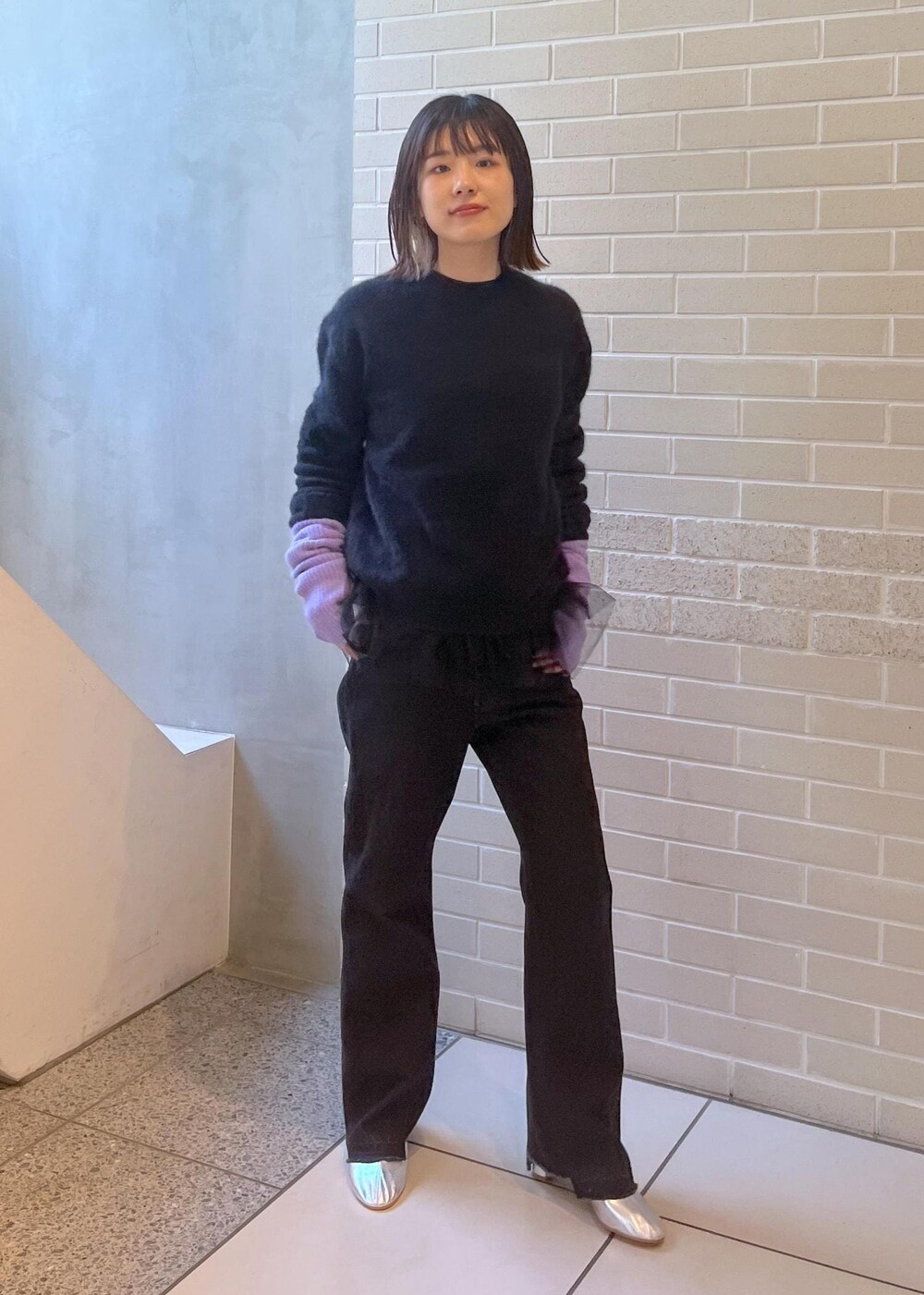 ブラック系のニット/セーター、ブラック系のベスト、グレー系のデニムパンツを着用したレディースの秋コーディネートの3枚目の写真