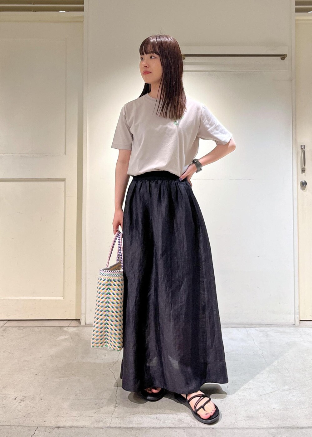 ブラック系のスカート、ベージュ系のTシャツ/カットソーを着用したレディースの夏コーディネートの3枚目の写真