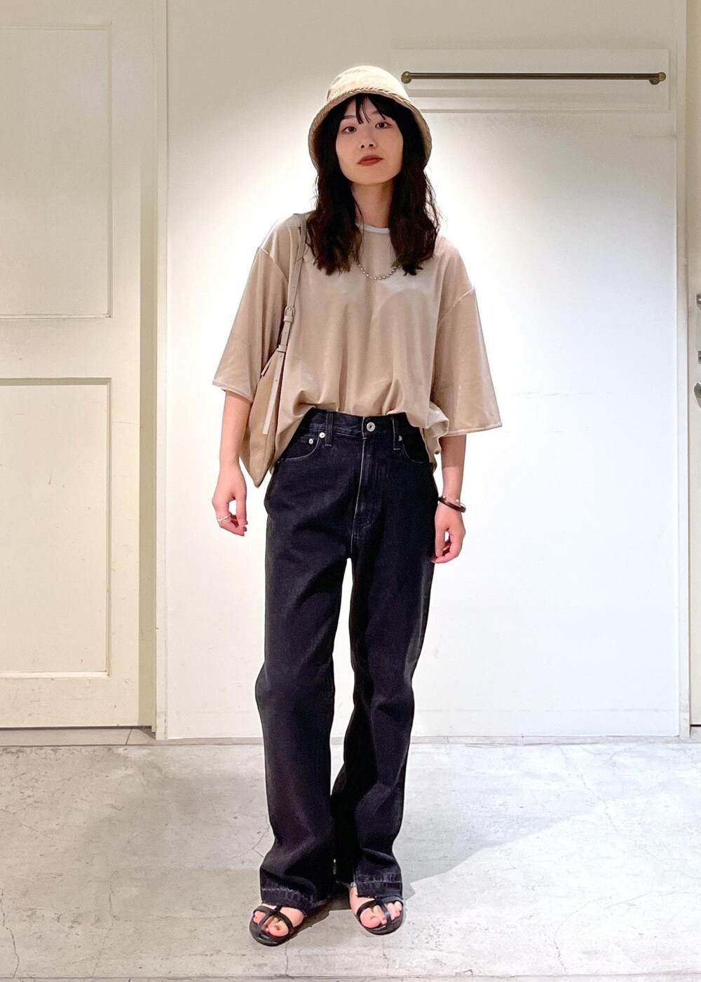 ブラック系のサンダル、グレー系のデニムパンツ、ベージュ系のTシャツ/カットソーを着用したレディースの夏コーディネートの7枚目の写真