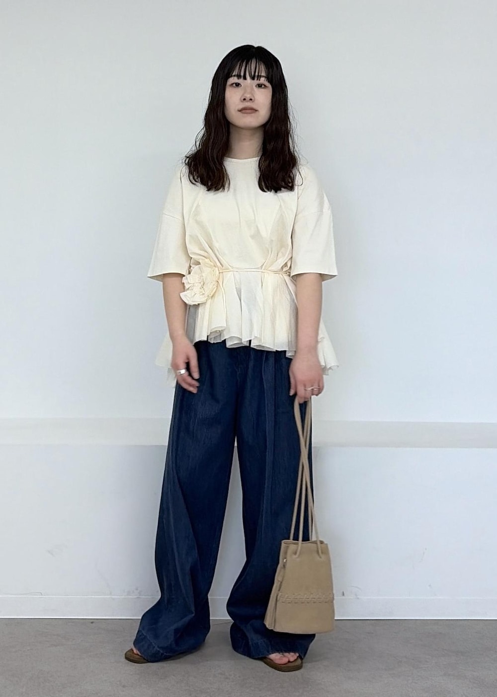 ベージュ系のショルダーバッグ、ブルー系のデニムパンツ、ブラウン系のサンダルを着用したレディースの冬コーディネートの6枚目の写真