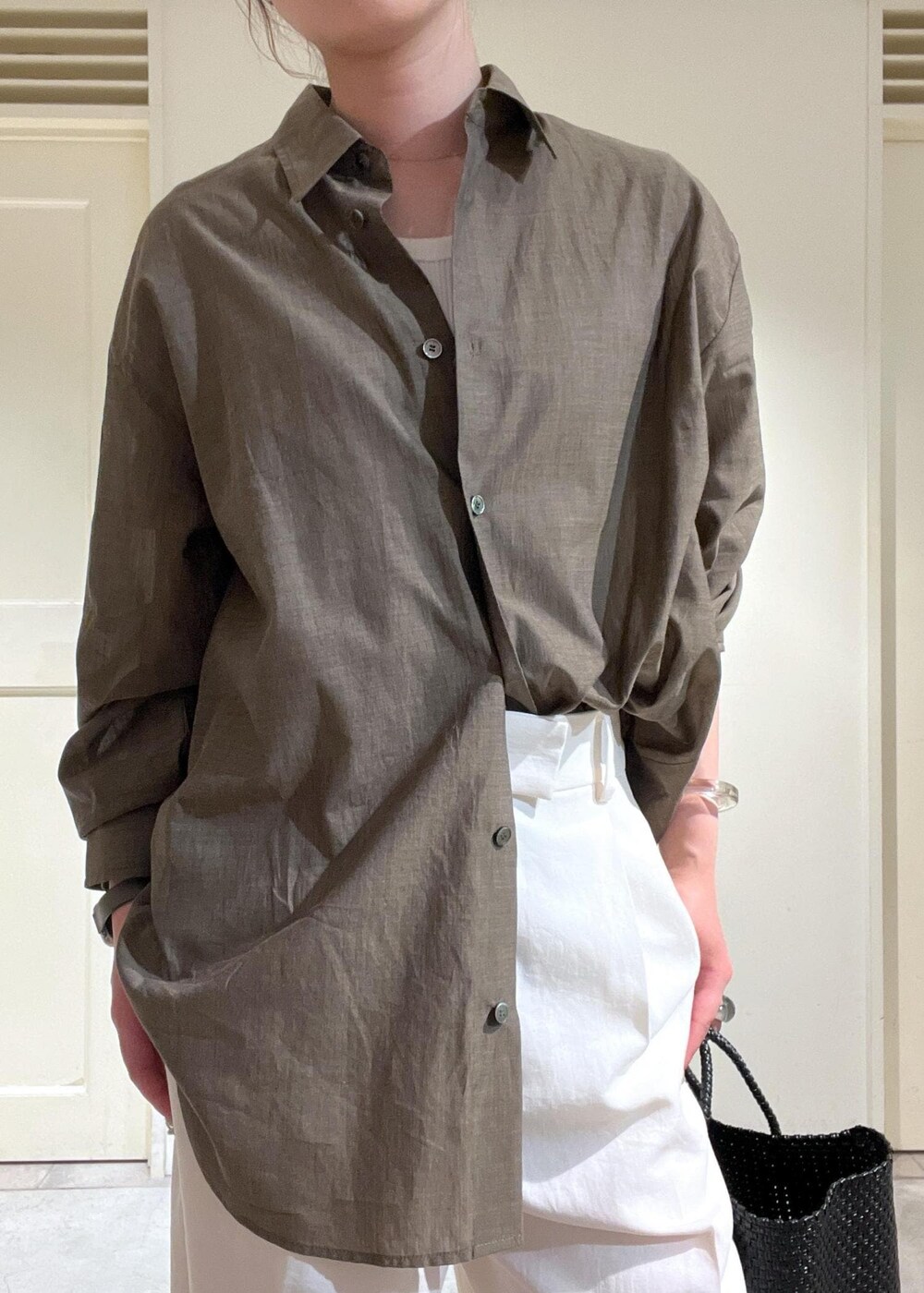 ブラウン系のシャツ/ブラウス、ホワイト系のTシャツ/カットソー、ブラック系のかごバッグを着用したレディースの春コーディネートの5枚目の写真